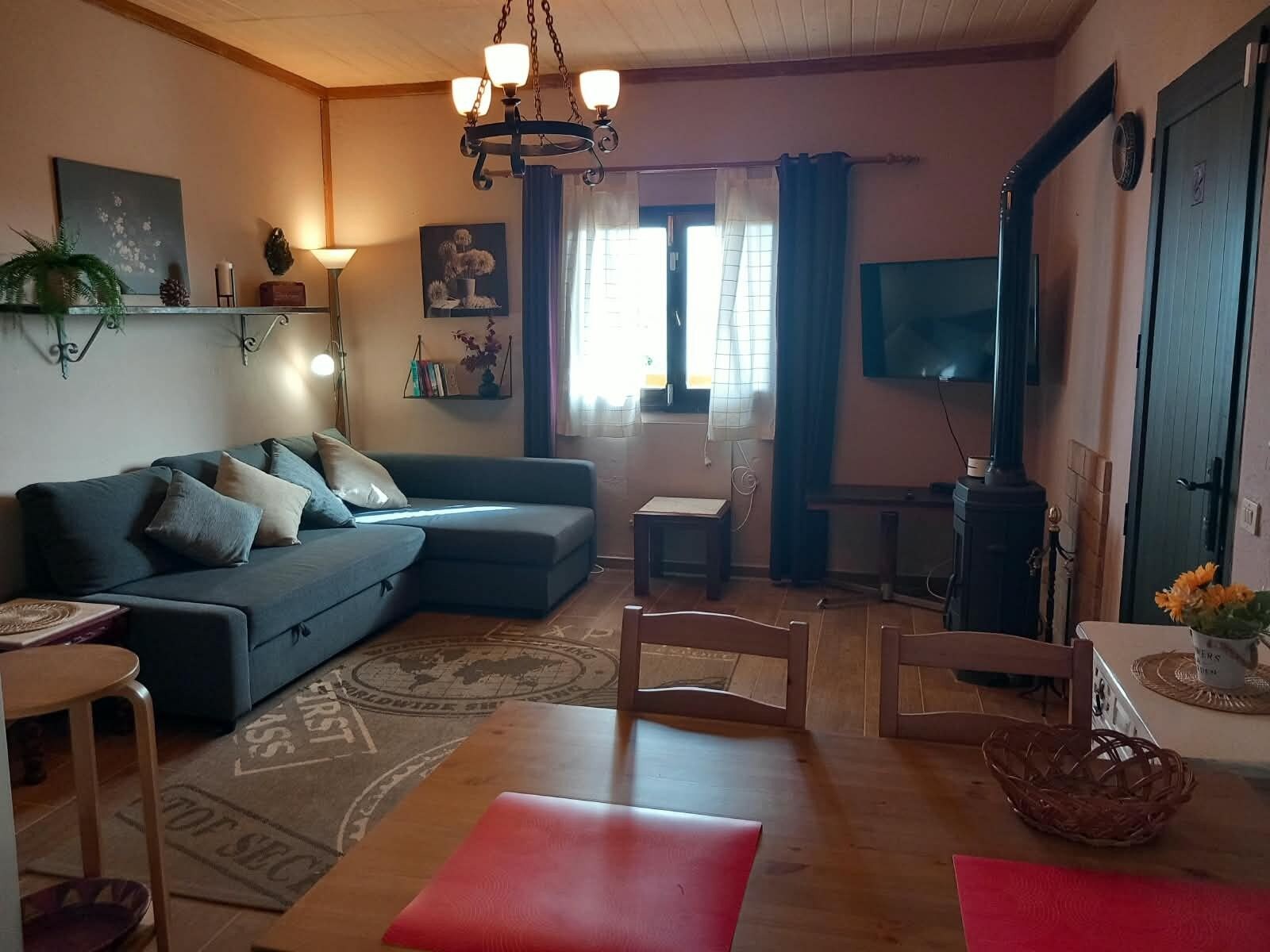 Een woonkamer met een bank, een televisie, een open haard en een eethoek met een tafel en stoelen.