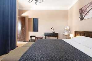 Una camera d'albergo con un letto, una scrivania, una sedia, una lampada e un quadro appeso al muro.
