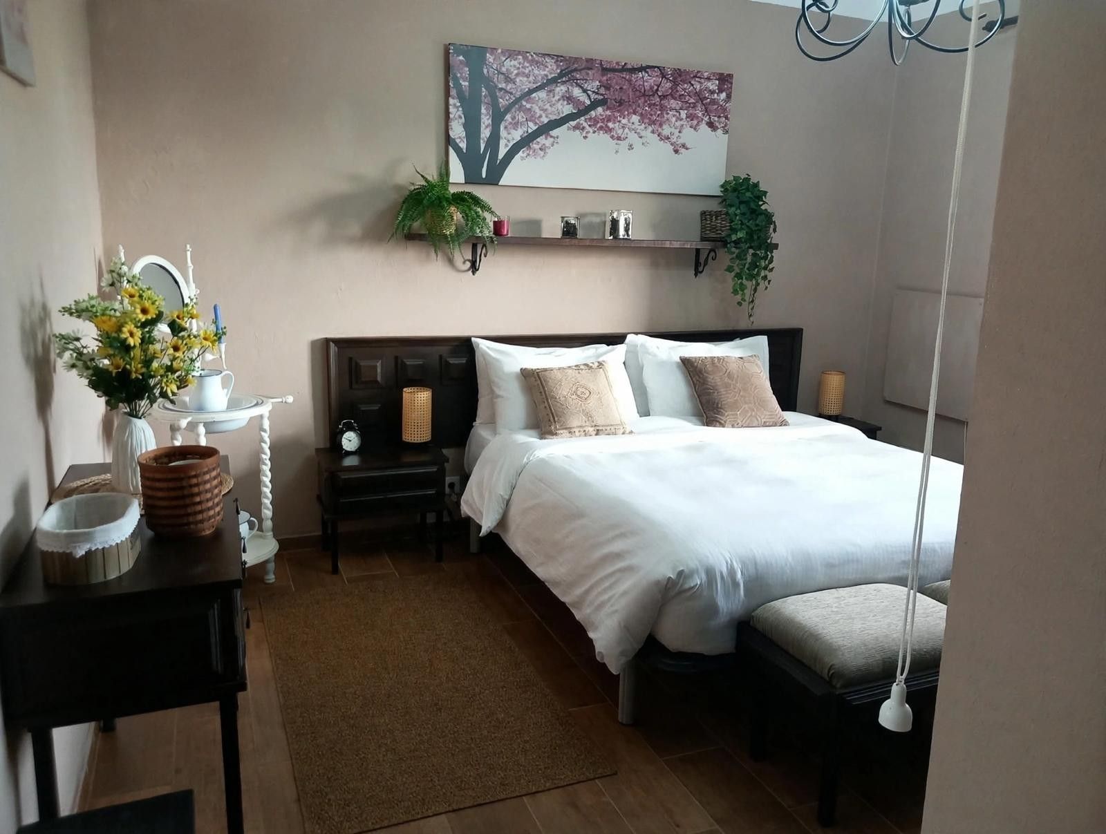 Een slaapkamer met een bed, nachtkastjes, een spiegel, een wandplank met decoratieve objecten en een hangplant.