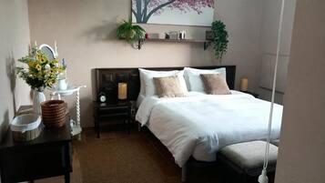 Een slaapkamer met een bed, nachtkastjes, een spiegel, een wandplank met decoratieve objecten en een hangplant.