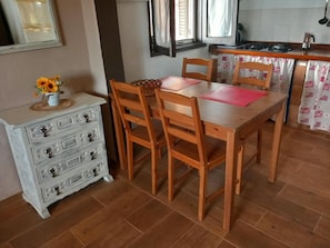 A dining area with a wooden table and chairs, a white dresser with drawers, and a vase of flowers. - Vacation Rental 'Apartamento Brownie' with Sea View, Private Terrace and Wi-Fi (Firgas)