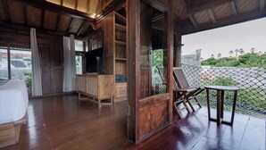 Ein Zimmer mit Holzboden, einem Fernseher, einer Couch und einem Tisch mit Stühlen.