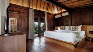 Ein Schlafzimmer aus Holz mit einem großen Bett, einem Nachttisch und einem Fenster mit Blick auf Grünflächen.