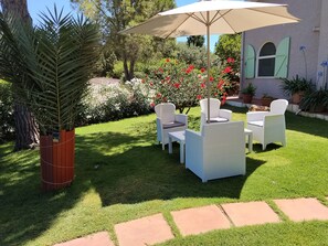 Un espace patio aménagé avec du mobilier d’extérieur, une pergola et diverses plantes.