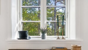 A room with a large window, a green mat, a book, a potted plant, and a candle holder.