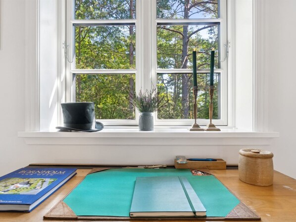 A room with a large window, a green mat, a book, a potted plant, and a candle holder.