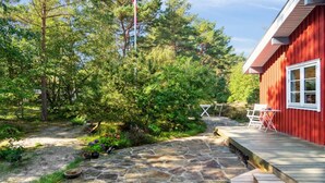 A stone pathway leading to a red wooden building with a deck and outdoor seating.