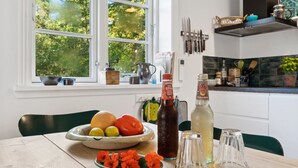 A kitchen with a window, a fruit bowl, a bottle of cola, and a bottle of tea.