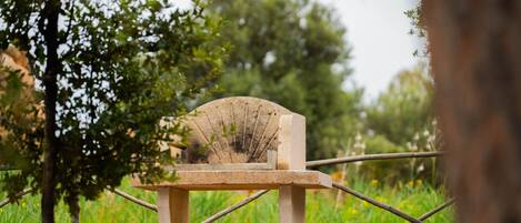 Un banco de piedra con respaldo curvo en un área verde al aire libre con árboles.