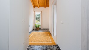 A hallway with a wooden ceiling, white walls, a patterned rug, and a potted plant. - "Domina" Holiday Home with Private Garden (Pula)