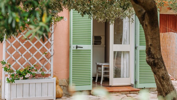 A quaint cottage with a wooden lattice, a white bench, and a door with green shutters. - "Domina" Holiday Home with Private Garden (Pula)