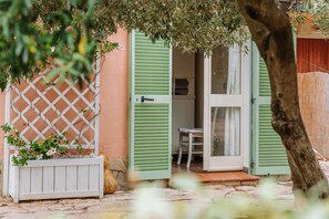 A quaint cottage with a wooden lattice, a white bench, and a door with green shutters. - "Domina" Holiday Home with Private Garden (Pula)