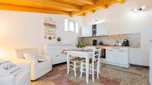 A kitchen with white cabinets, a wooden ceiling, a dining table with chairs, and a coffee machine. - "Domina" Holiday Home with Private Garden (Pula)