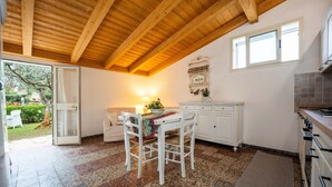 A kitchen with a wooden ceiling, a dining table with chairs, a window, and a tiled floor. - "Domina" Holiday Home with Private Garden (Pula)