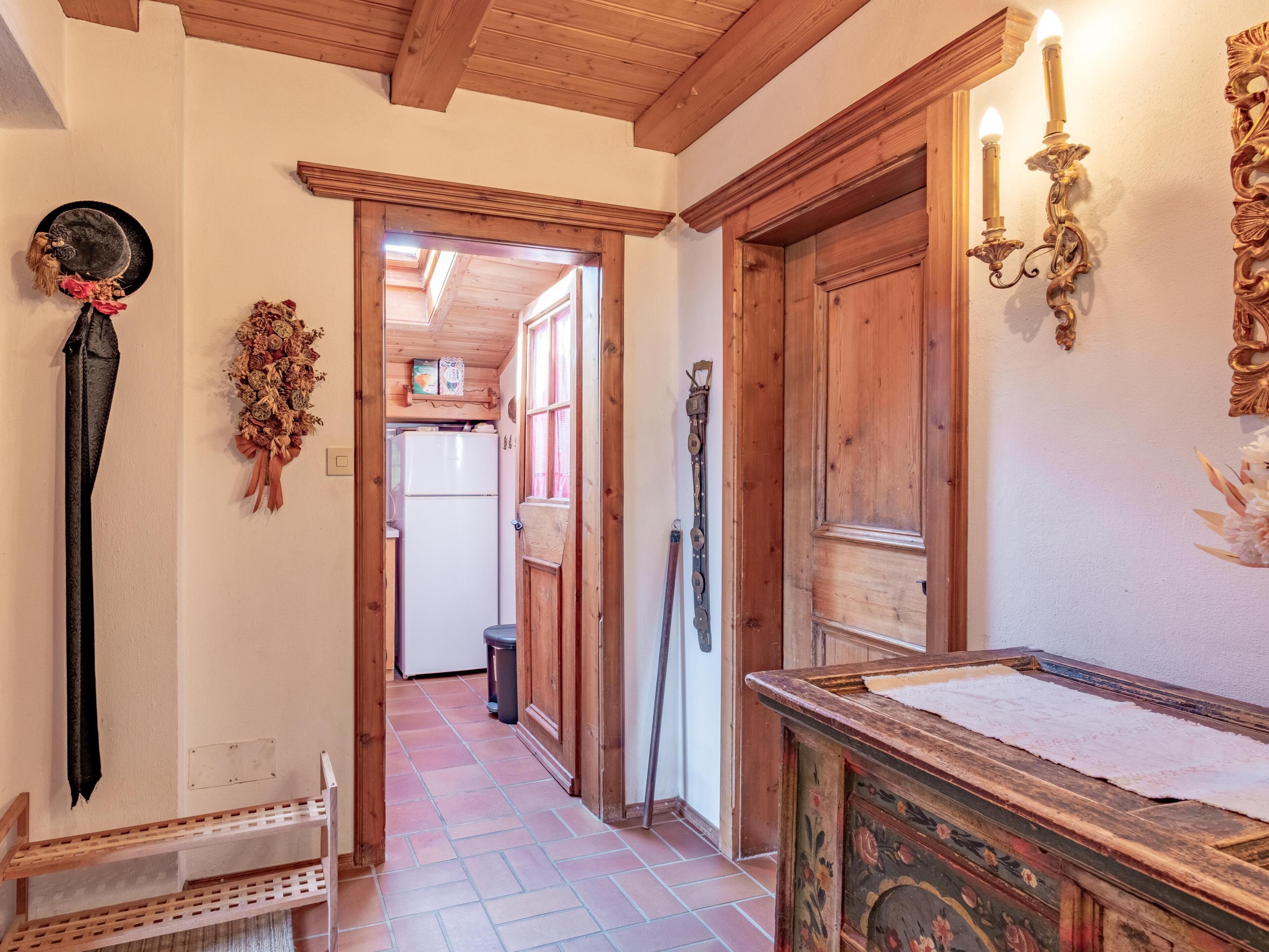 A narrow hallway with wooden doors and walls, a wooden bench, and a decorative wall piece.