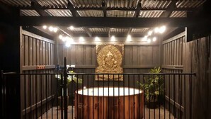 A spa area with a hot tub, a wooden fence, and a decorative wall. - Blacksmith Corner (Nannup)