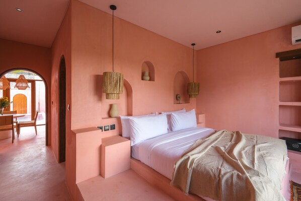 Un dormitorio con una cama grande, una mesita de noche y una estantería en la pared.