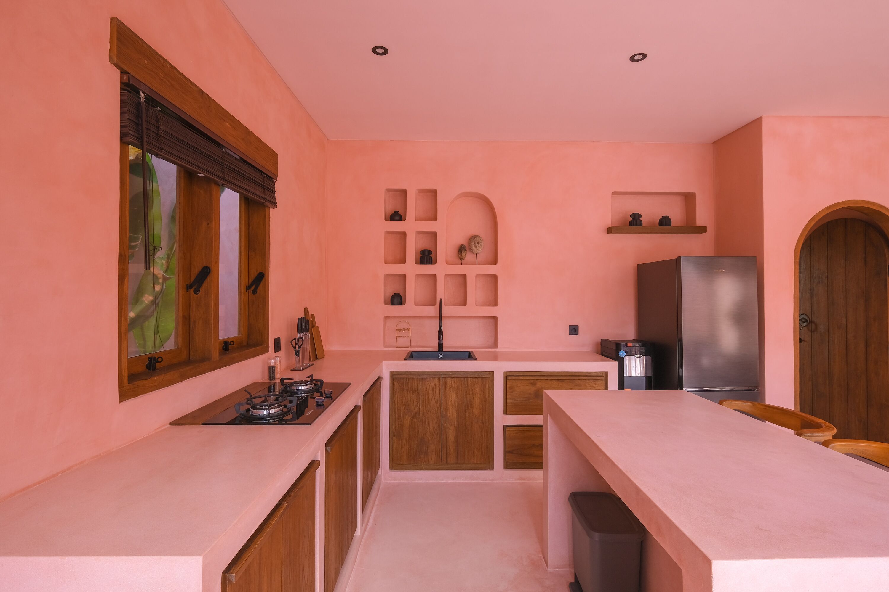 A compact kitchen with a central island, wooden cabinets, a built-in oven, and a stainless steel refrigerator.