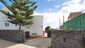 Un bâtiment moderne avec un mur en pierre, un arbre et un ciel dégagé.