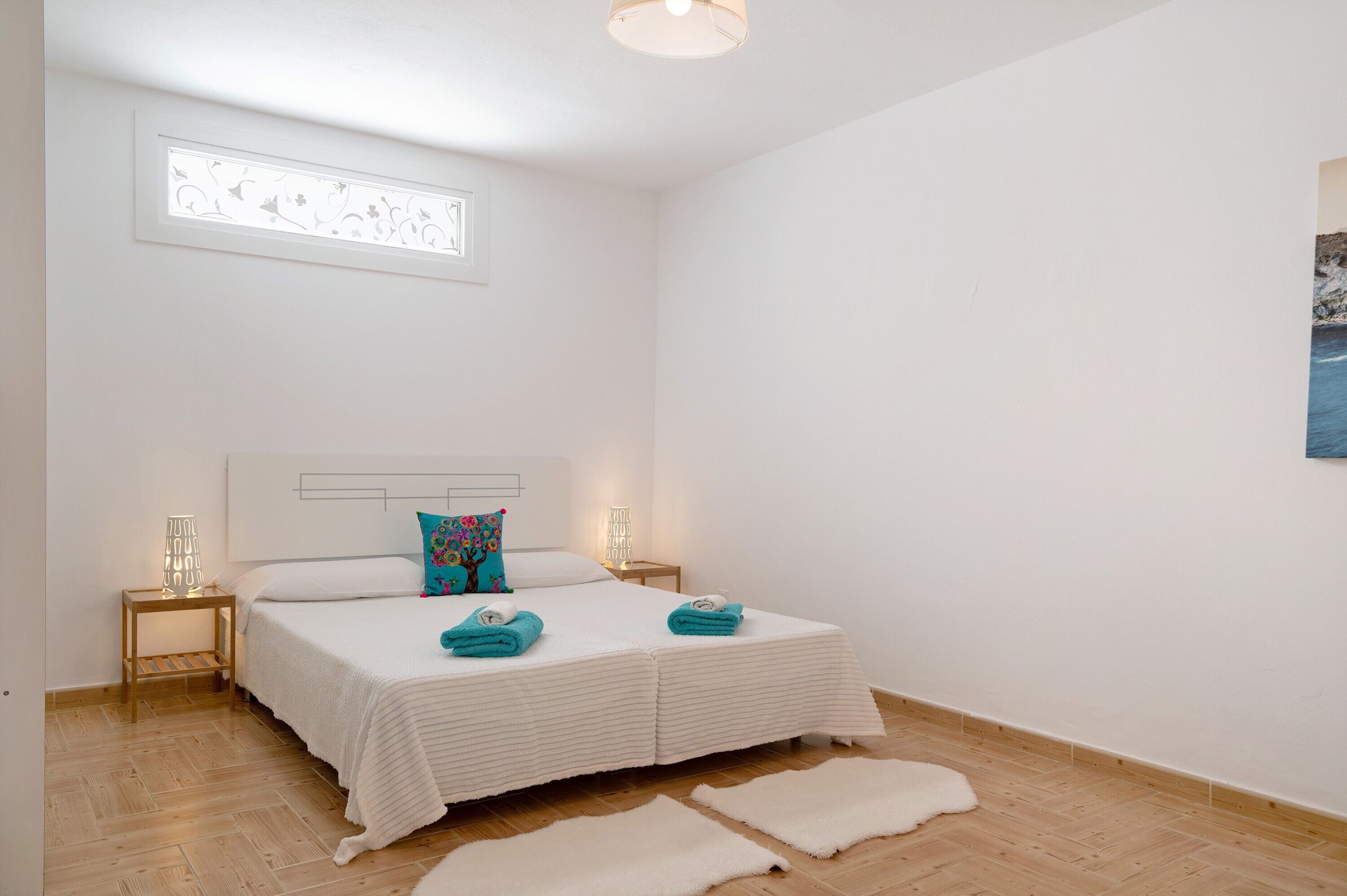 Een slaapkamer met een bed, twee nachtkastjes, een wandlamp en een raam met uitzicht.