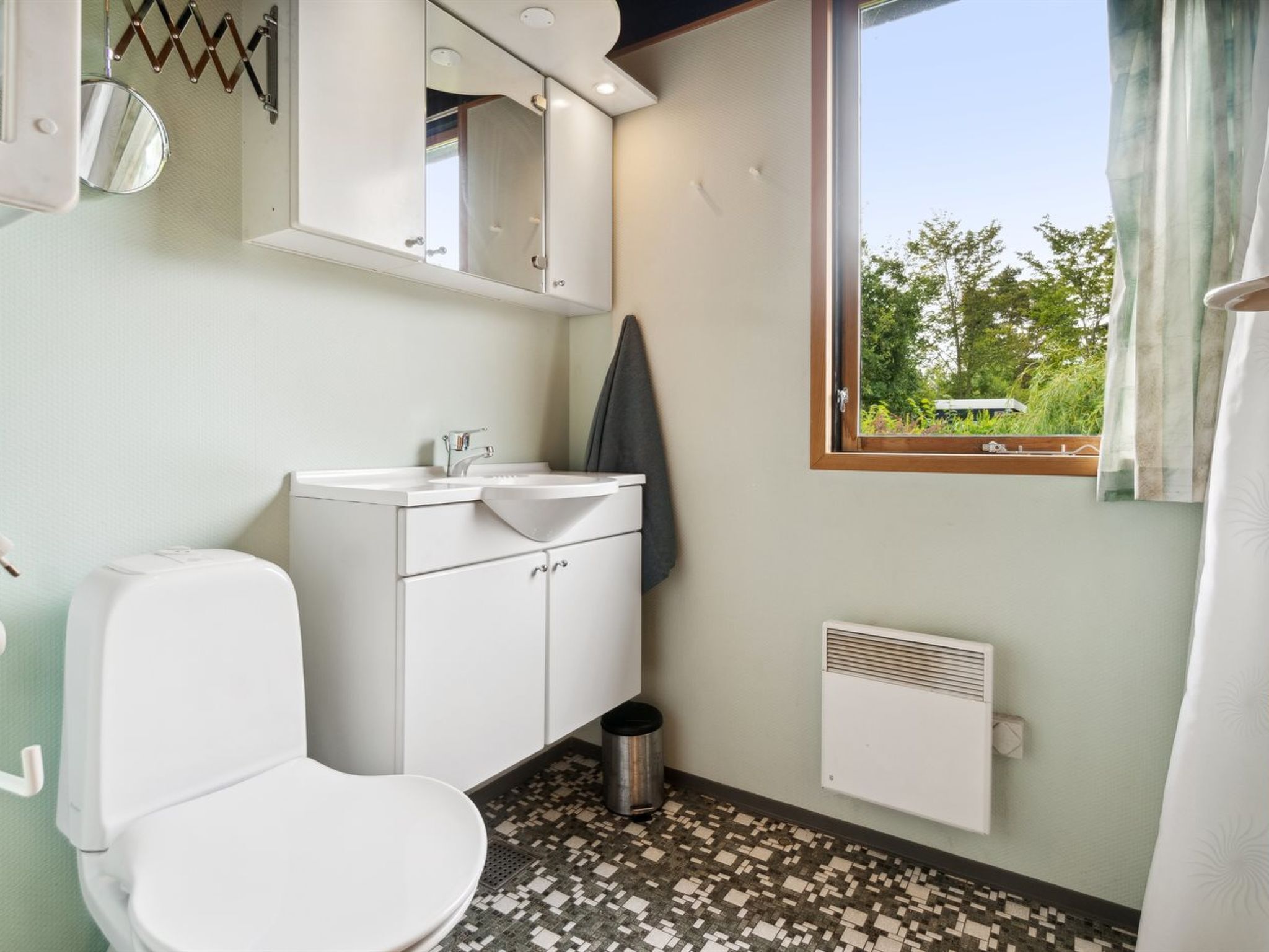 Une salle de bain équipée de toilettes, d’un lavabo, d’un miroir et d’une fenêtre.