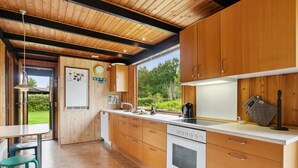 Una cocina moderna con armarios de madera, estufa de acero inoxidable y un amplio ventanal con vistas al exterior.