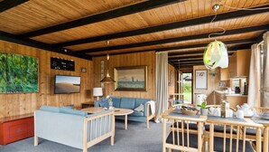 Interior acogedor de una cabaña con un sofá azul, una mesa de comedor de madera y una zona de cocina.