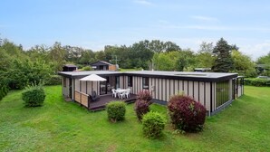 Una casa moderna con terraza, un patio con mobiliario exterior y un jardín bien cuidado.