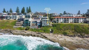 Un hôtel situé sur la côte, composé de plusieurs bâtiments, avec un rivage rocheux et des vagues déferlantes sur l’océan.