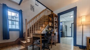 A home interior with a wooden staircase, a desk with a chair, a refrigerator, and a lamp. - Modern Downtown Escape HotTub Fire Pit Games 12ppl (Keene)