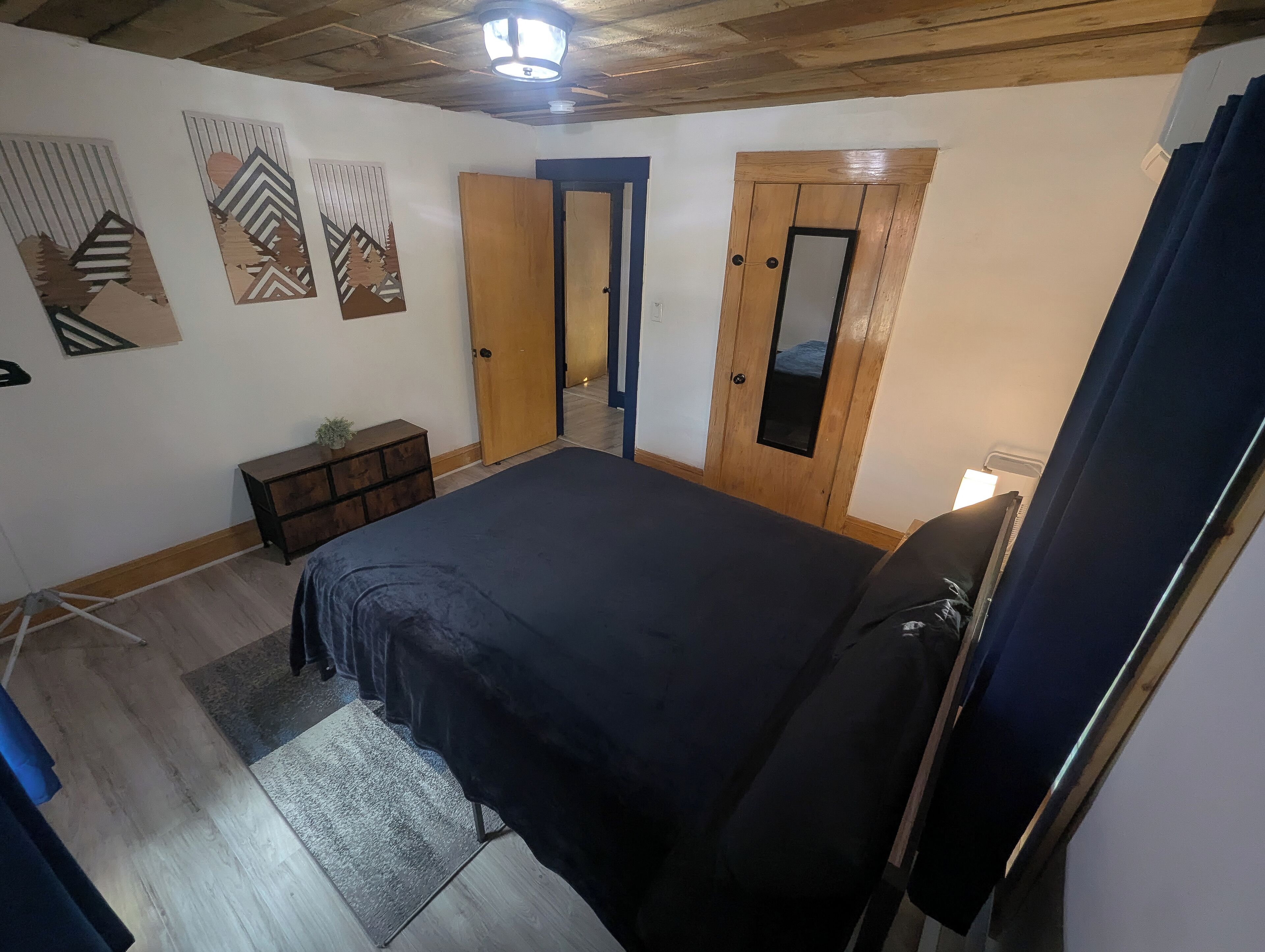 Ein Schlafzimmer mit einem Bett, einem Holzschrank und einem Spiegel.