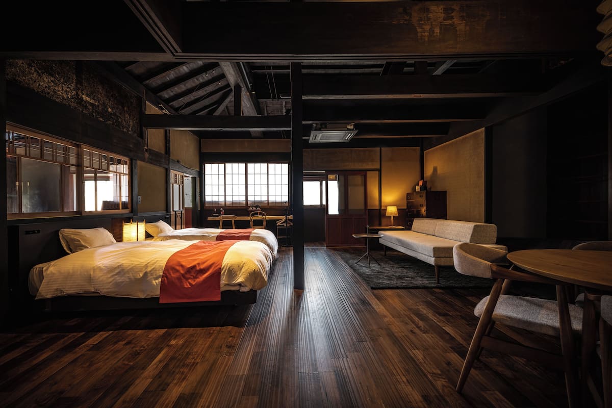 Une chambre d’hôtel avec deux lits, un canapé, une petite table et un bureau.