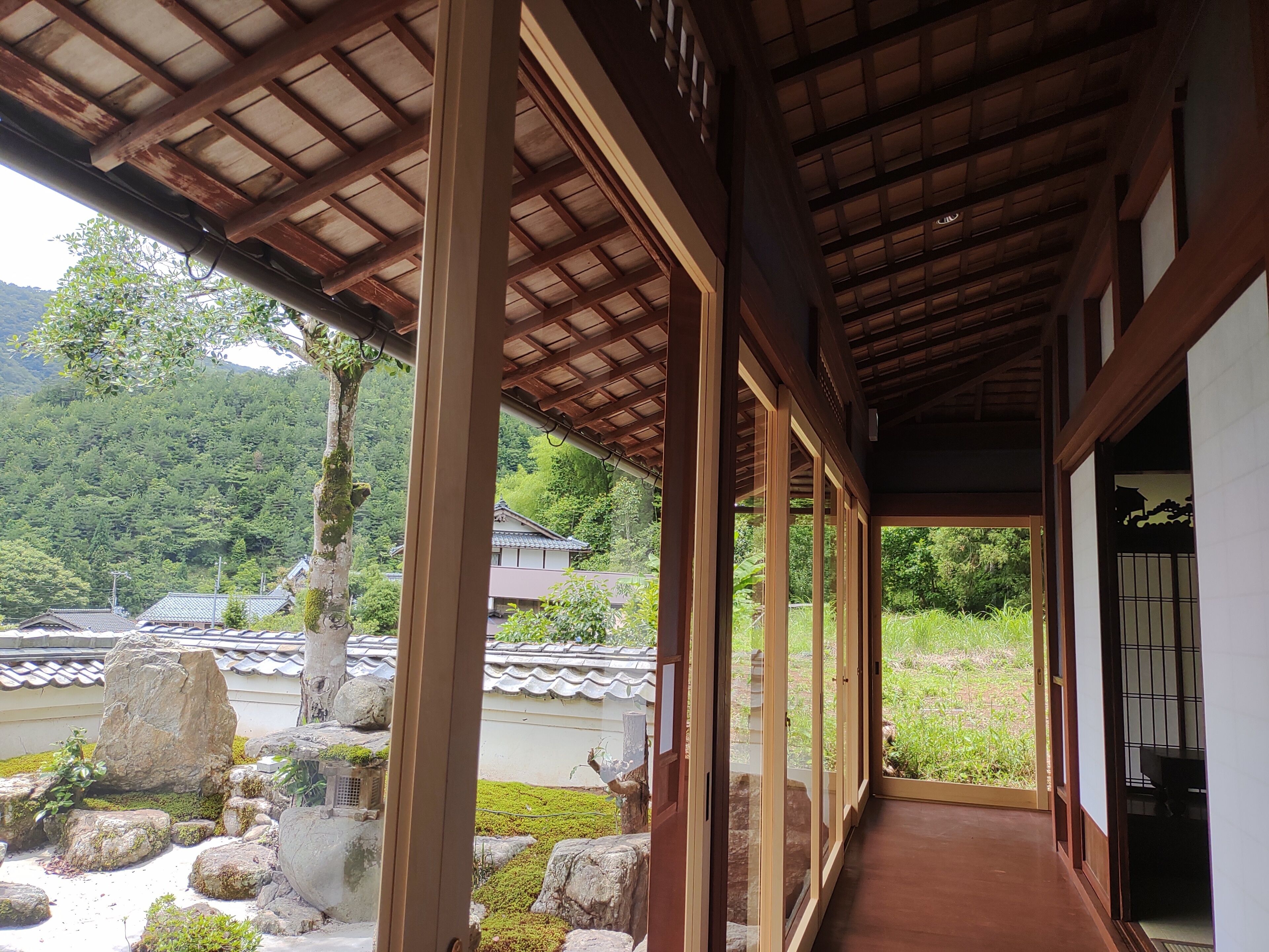 Un edificio japonés tradicional con un corredor cubierto, vigas de madera y vistas a un paisaje montañoso.