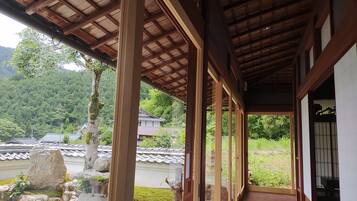 Un edificio japonés tradicional con un corredor cubierto, vigas de madera y vistas a un paisaje montañoso.