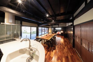 A modern kitchen with a wooden dining table, large windows, and a view of the outdoors.