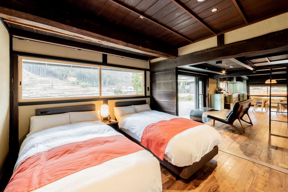 Une chambre d’hôtel moderne avec deux lits, un coin repas et une vue sur l’extérieur.