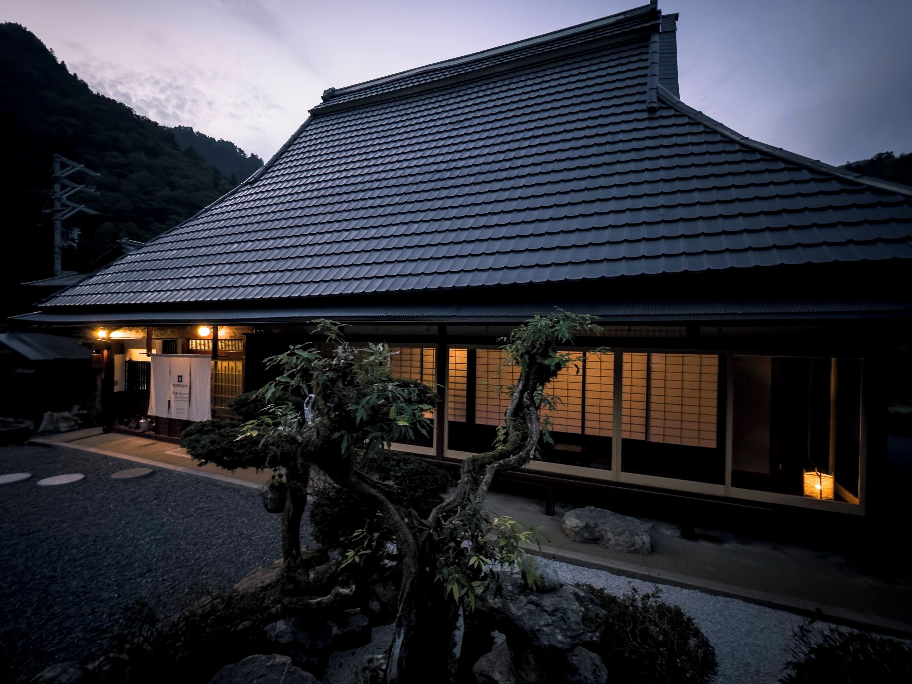 A traditional Japanese building with a tiled roof and a well-maintained garden in front.