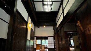 Een traditioneel Japans interieur met tatami vloeren, schuifdeuren en uitzicht op een kamer met een houten tafel en stoelen.