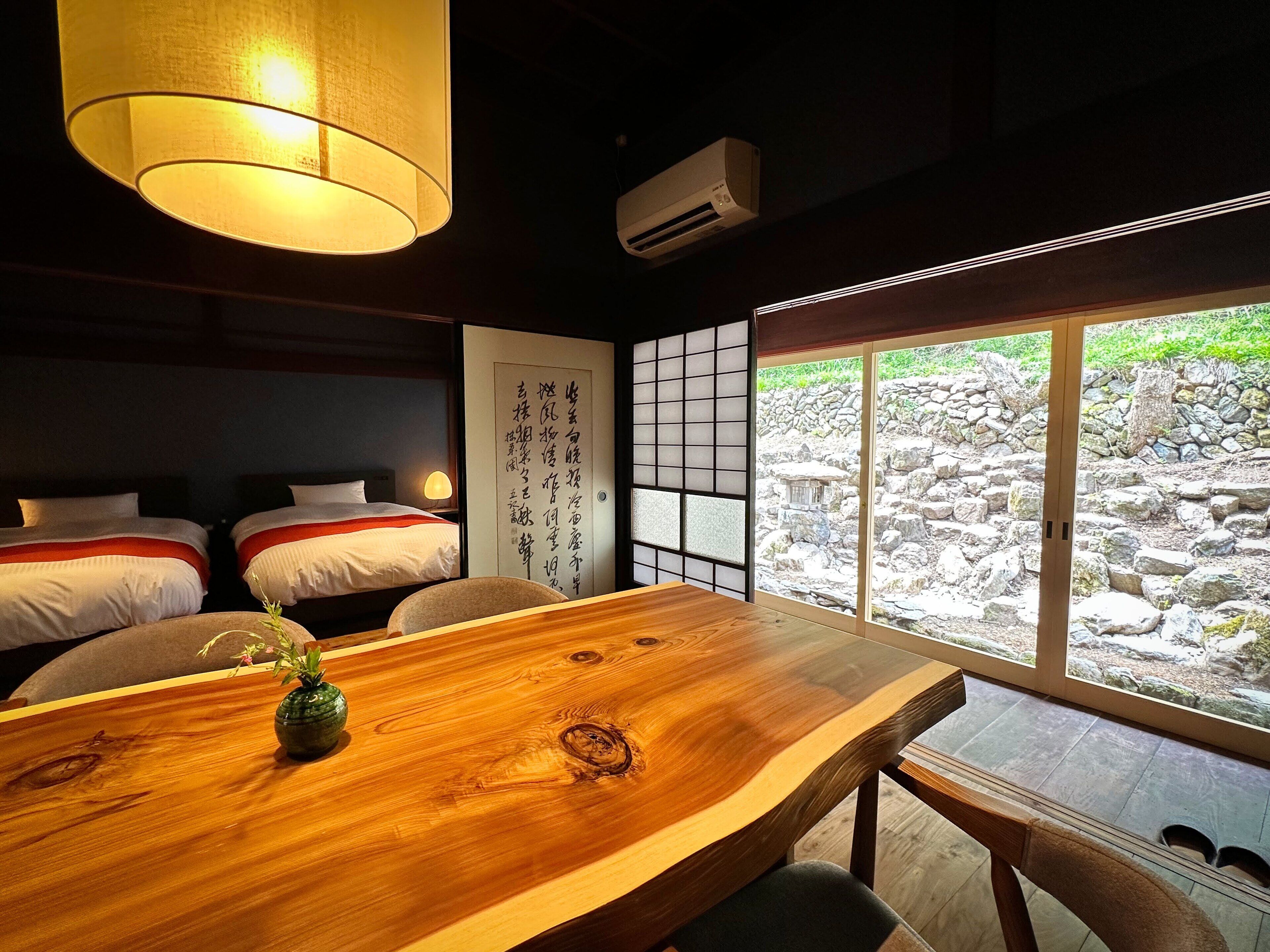 A traditional Japanese-style room with tatami mats, a wooden table, and a view of a stone garden.