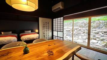 A traditional Japanese-style room with tatami mats, a wooden table, and a view of a stone garden.