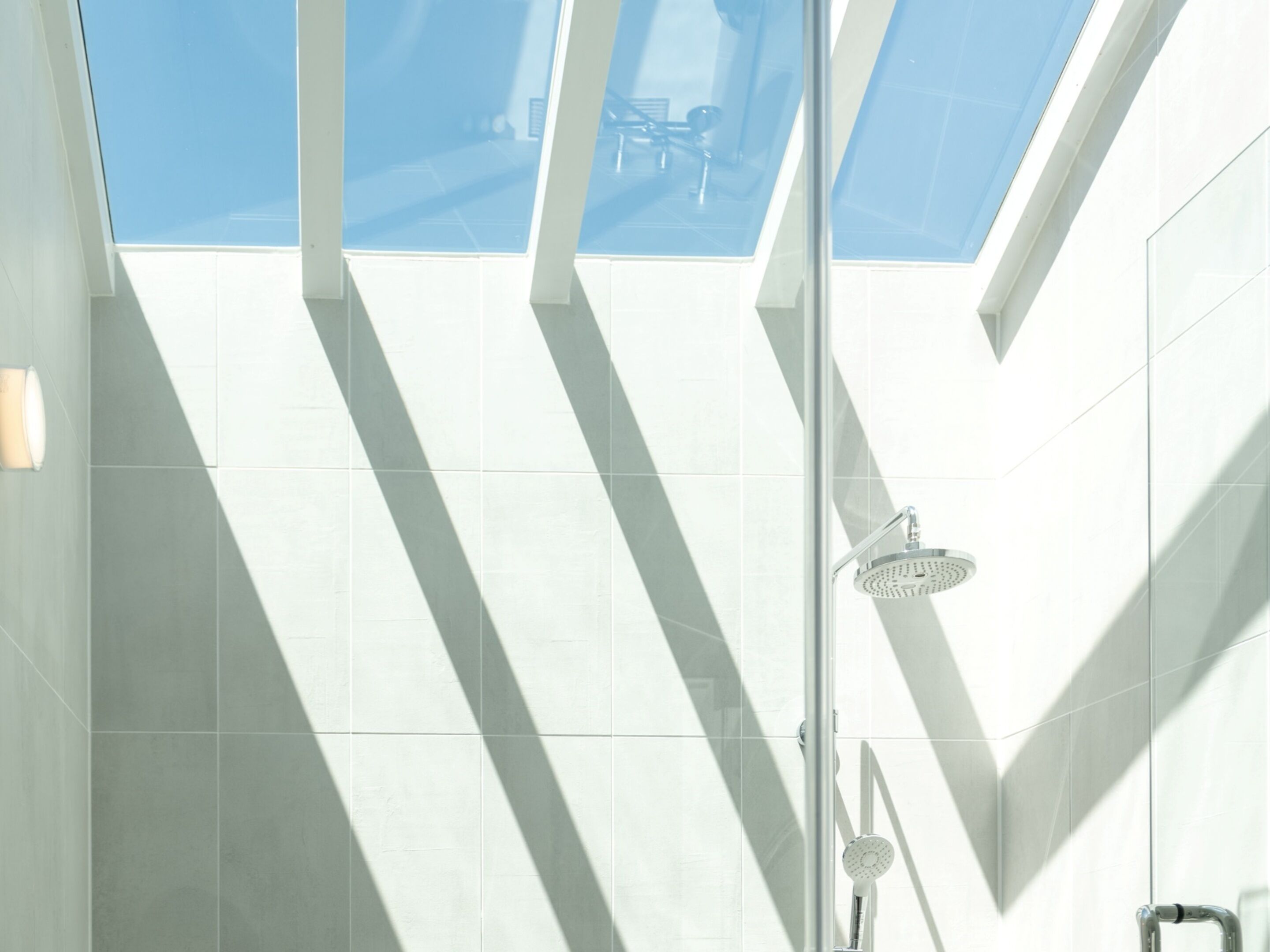 Een moderne douche met een glazen plafond, waardoor natuurlijk licht binnenvalt.