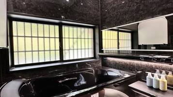 Un baño moderno con encimera de mármol negro, un espejo grande y una ventana con vidrio esmerilado.