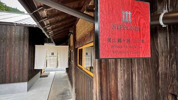 Ein Holzgebäude mit einem roten Schild, auf dem „NIPPONIA MIYAMA TSURUGAOKA MOUNTAIN VILLAGE“ steht.