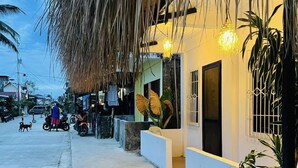 A beachfront property with a thatched roof, a concrete pathway, and a view of the sea. - Islescape Siargao (General Luna)