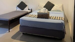 A small, single-room accommodation with a bed, a bedside table, and a wall-mounted heater. - Islescape Siargao (General Luna)