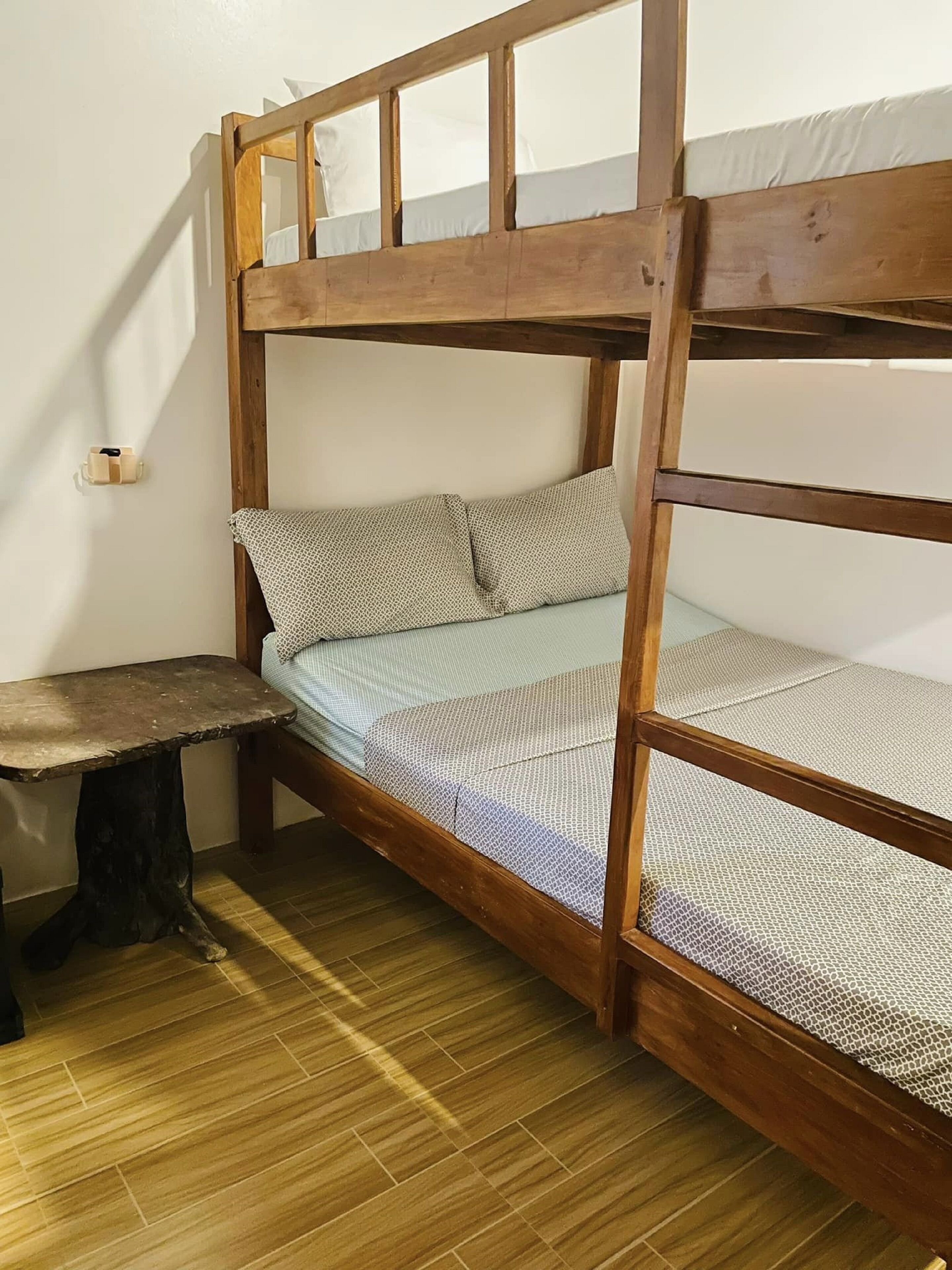 Un lit superposé avec une structure en bois, une petite table et une couvre-lit à motifs.