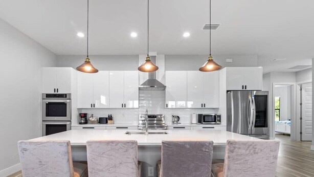 A modern kitchen with white cabinets, stainless steel appliances, and a central island with bar stools. - Tranquil location Close to Beaches Lake Front (Rotonda West)