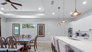 A modern kitchen with white cabinets, a central island with a sink, and pendant lighting. - Tranquil location Close to Beaches Lake Front (Rotonda West)