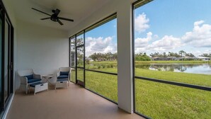 A balcony with two wicker chairs and a small table, overlooking a grassy area and a body of water. - Tranquil location Close to Beaches Lake Front (Rotonda West)