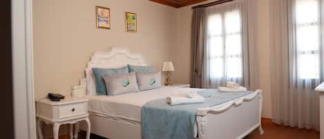 Une chambre à coucher bien rangée, avec un lit, des tables de chevet, une lampe et deux œuvres d’art encadrées accrochées au mur.